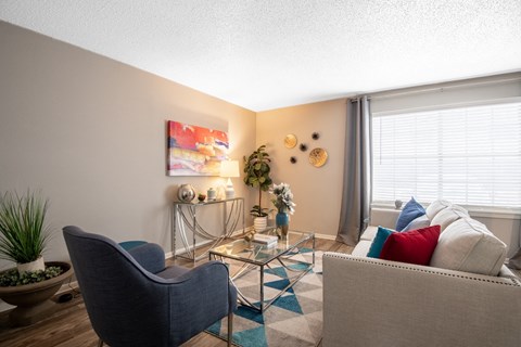 luxurious Stadium 700 Apartments lofts in Arlington tx with glass table, blue chair, and large window with drapes.